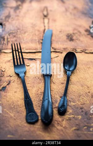 Forchetta e cucchiaio di coltello nero vintage su ardesia di rame Foto Stock
