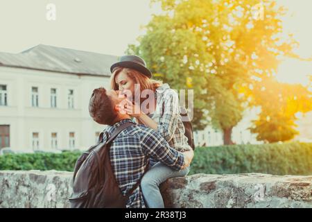 Coppia emotivo kissing seduta sul vecchio muro di pietra Foto Stock