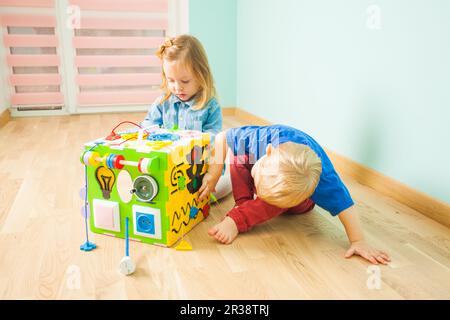 Due bambini seduti su un pavimento in prossimità di grandi toy Foto Stock