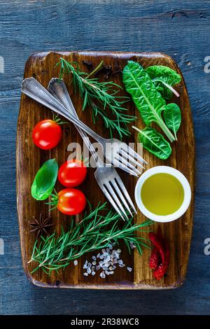 Tagliere in legno d'epoca e ingredienti freschi per una cucina sana su fondo rustico scuro Foto Stock