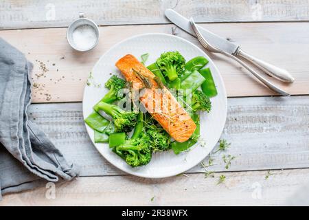 Salmone su un letto di verdure verdi con tout di mange Foto Stock