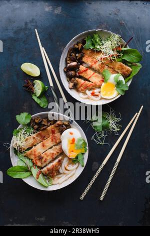 Zuppa di noodle Udon con scaloppa Katsu, bietole, uova, funghi fritti, coriandolo, germogli di lime e cipolle Foto Stock