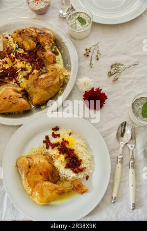 Zereshk Polo ba Morgh (cosce di pollo brasate allo zafferano su riso al mirtillo, Persia) Foto Stock