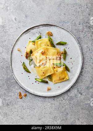 Ravioli di capra con asparagi verdi, noci, peperoncini e olio d'oliva Foto Stock