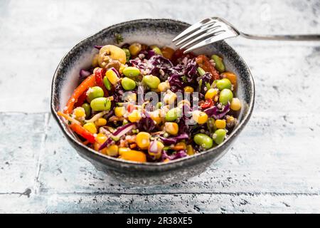 Insalata di quinoa colorata con pomodori, mais dolce, edamame, cavolo rosso, ceci torrefatti e carote Foto Stock