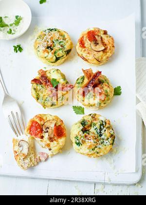 Muffin frittata con pancetta, pomodori, funghi e zucchine Foto Stock