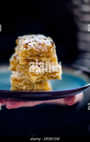 Una mano che tiene tre fette di torta crumble di mela su un vassoio Foto Stock