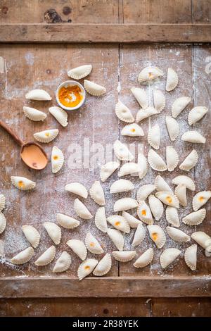 Pierogi non cotti ripieni di curcuma su un asse di legno Foto Stock