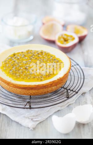 Cheesecake con frutto della passione su una rastrelliera metallica e vari ingredienti da forno Foto Stock