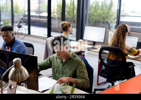 Occupati diversi uomini d'affari che lavorano alla scrivania utilizzando computer in ufficio creativo, inalterato Foto Stock