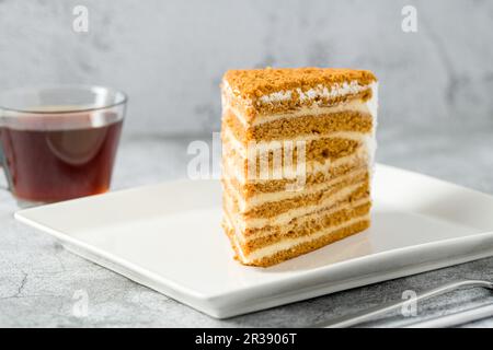 Fetta di torta di miele su piatto di porcellana bianca su sfondo di pietra Medovik Foto Stock