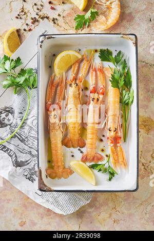 Langostine in vassoio di raccolta con limone, prezzemolo e olio d'oliva Foto Stock