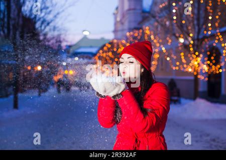 Giovane ragazza che soffia via la neve dai mitens Foto Stock