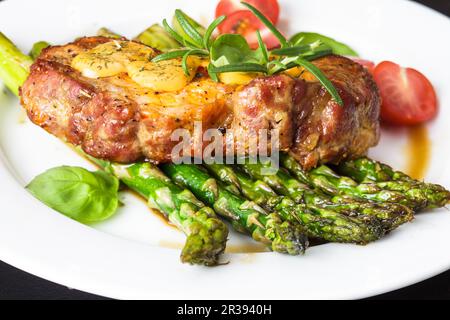 Bistecca gourmet con asparagi verdi sul piatto Foto Stock