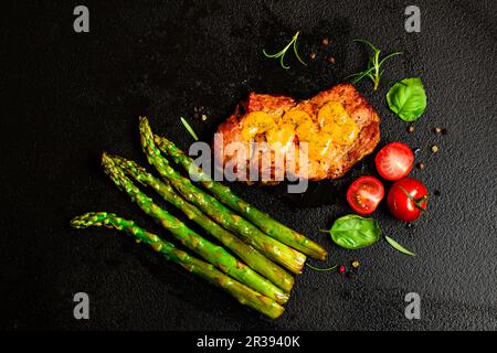 Carne di maiale alla griglia con asparagi e pomodori Foto Stock