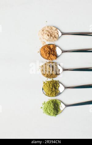 Cucchiai con diverse polveri colorate superfood sul tavolo Foto Stock