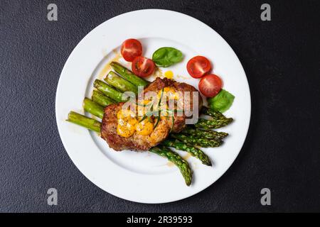 Bistecca gourmet con asparagi verdi sul piatto Foto Stock