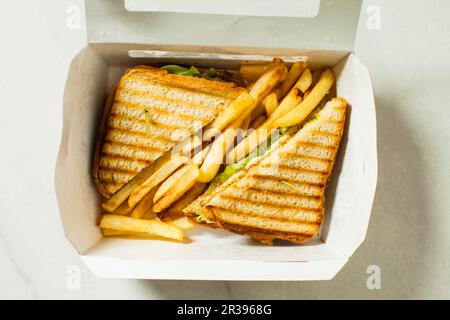 Scatola di carta con sandwich di pollo con patatine fritte Foto Stock