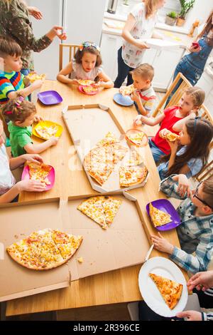 I bambini mangiano la pizza in casa, festa per i bambini Foto Stock