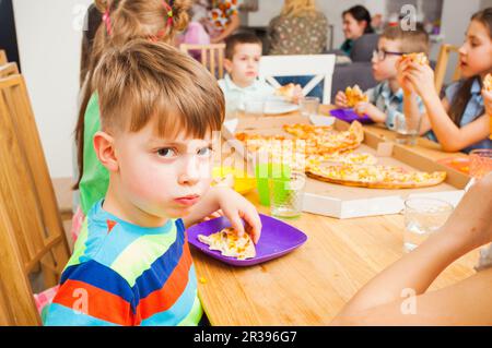 I bambini mangiano la pizza durante la riunione dei bambini Foto Stock