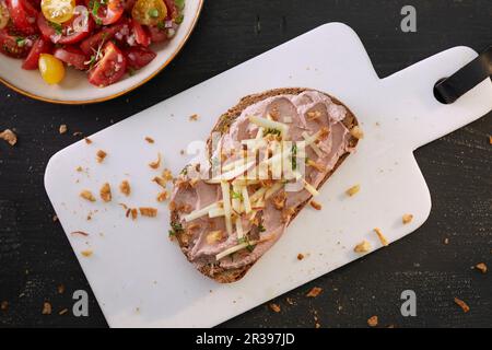 Una fetta di pane spalmata con pâté di fegato e mela, servita con insalata di pomodoro Foto Stock