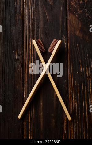 Due spazzolini da denti in bambù su sfondo di legno nero Foto Stock