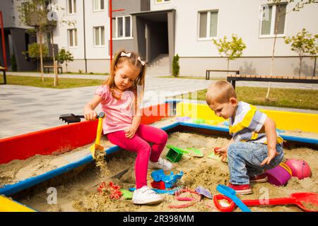 Bambina giocare Sandbox Parco giochi Digging sabbia Shovel costruzione  sabbia Figura giorno estivo. Caucasica femmina Bambini 5 anni divertirsi  all'aperto Foto stock - Alamy