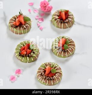 Mattcha vegana e torte al cioccolato con glassa al cioccolato bianco e fragole fresche Foto Stock