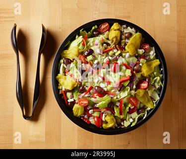 Insalata greca con pinze in plastica shot sul tavolo blocco macellaio dall'alto Foto Stock