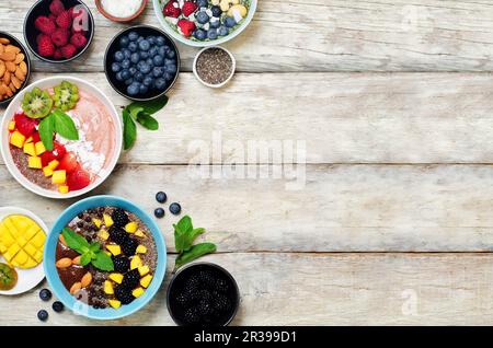 Varie ciotole e ingredienti per la colazione su un tavolo di legno bianco Foto Stock