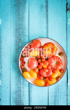 Pomodori colorati su un tavolo di legno blu Foto Stock