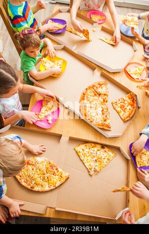 Top visualizza immagine dei bambini prendere fette di pizza dal riquadro alla cucina. Foto Stock