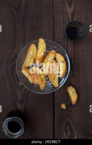 Biscotti di mandorle italiane detti Cantuccini su un piatto, serviti con un caffè su un tavolo di legno Foto Stock