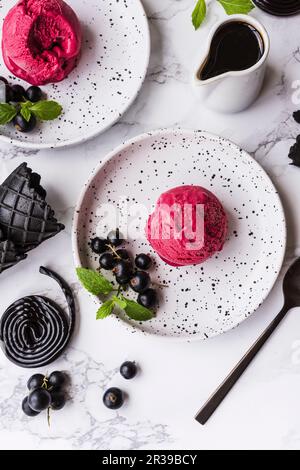 Gelato alla liquirizia con ribes neri su piatti da dessert bianchi Foto Stock