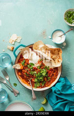 Peperoncino con pomodori, peperoni, aglio e paprika affumicata, panna acida, coriandolo e pane piatto Foto Stock