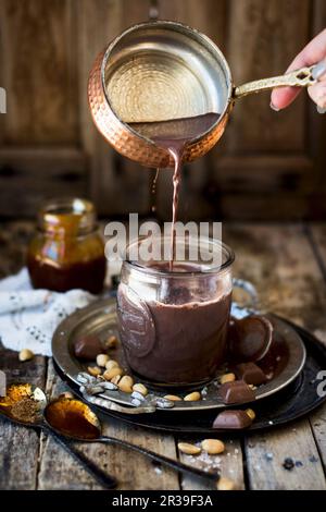 Cioccolata calda con caramello di arachidi versato in una tazza Foto Stock