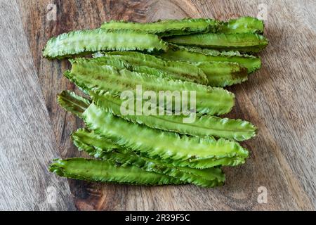 Fagioli freschi alati su una superficie di legno Foto Stock