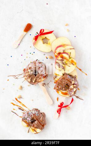 Fette di mela caramellate su un bastone con noci e Sprinkles colorati Foto Stock
