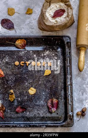 Biscotti sotto forma di lettere da cui la parola ottobre è disposta su un deco con le foglie gialle Foto Stock