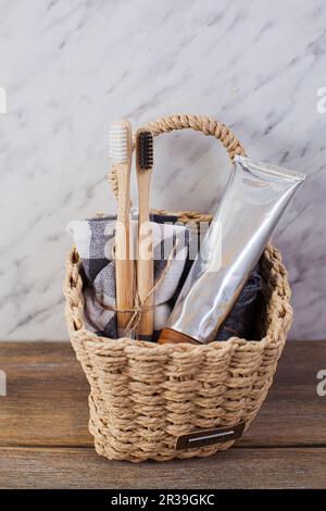 Spazzolini da denti in bambù naturale eco e dentifricio organico in un cesto in bagno. Foto Stock