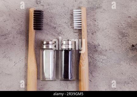 Zero rifiuti self-care prodotti. Dentifrici in bambù bianco, nero e filo di lino su fondo di cemento grigio Foto Stock