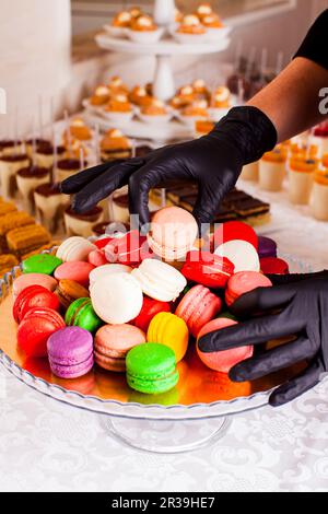 Catering bar per festeggiare. Macaroni colorati su un piatto. Gustosi dessert serviti al tavolo Foto Stock