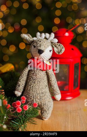 Il cervo giocattolo lavorato a maglia cute sullo sfondo dell'albero di Natale Foto Stock