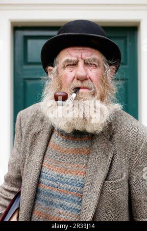 Il personaggio locale John Callaby nella foto si trova al di fuori dell'Alford Manor House nell'Alford Lincolnshire. John è ben noto ad Alford e si trova spesso fuori dalla Manor House e su panchine nel centro della città. E' ben noto per la sua caratteristica barba, cappello e pipa. E' piu' che felice di posare per fotografie ed e' parte della comunita' locale. Foto Stock