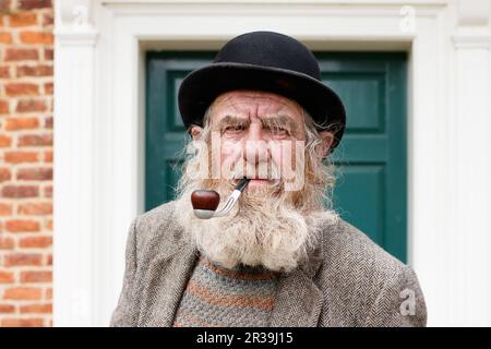 Il personaggio locale John Callaby nella foto si trova al di fuori dell'Alford Manor House nell'Alford Lincolnshire. John è ben noto ad Alford e si trova spesso fuori dalla Manor House e su panchine nel centro della città. E' ben noto per la sua caratteristica barba, cappello e pipa. E' piu' che felice di posare per fotografie ed e' parte della comunita' locale. Foto Stock