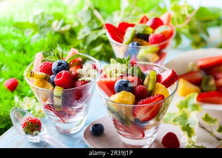 Sana insalata di frutta fresca e frutti di bosco con fragole, lamponi, kiwi, ananas, mirtilli e anguria su un tavolo all'aperto Foto Stock