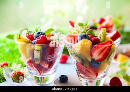 Sana insalata di frutta fresca e frutti di bosco con fragole, lamponi, kiwi, ananas, mirtilli e anguria su un tavolo all'aperto Foto Stock