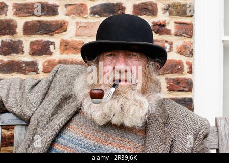 Il personaggio locale John Callaby nella foto si trova al di fuori dell'Alford Manor House nell'Alford Lincolnshire. John è ben noto ad Alford e si trova spesso fuori dalla Manor House e su panchine nel centro della città. E' ben noto per la sua caratteristica barba, cappello e pipa. E' piu' che felice di posare per fotografie ed e' parte della comunita' locale. Foto Stock