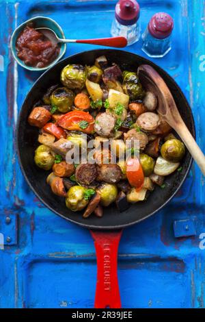 Salsicce con germogli di bruxelles, patate dolci e pomodori Foto Stock
