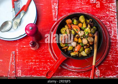 Salsicce con germogli di bruxelles, patate dolci e pomodori Foto Stock